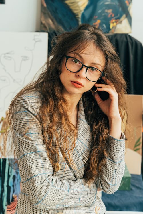 Free Portrait of a stylish woman with eyeglasses in an art studio, showcasing creativity. Stock Photo