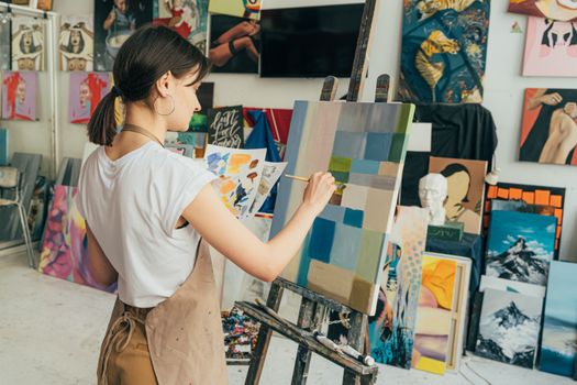 在充满活力和创意的工作室环境中，女艺术家在画布上作画，展示着她的艺术技巧