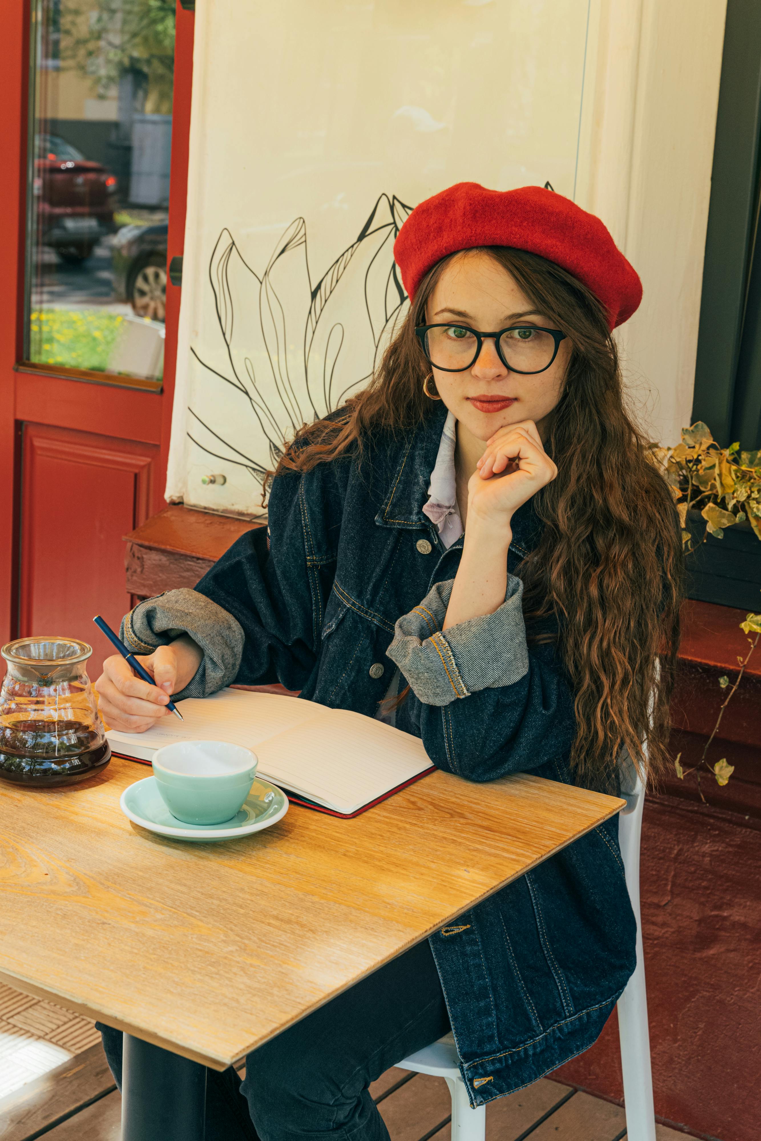 woman sitting at a table writing on a notebook