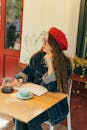 一名戴着红色贝雷帽和牛仔夹克的女子正在户外笔记本上写字