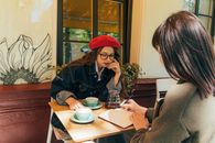 两名女子在一家别致的户外咖啡馆里边讨论边做笔记