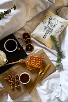 Enjoy a cozy breakfast in bed with waffles, honey, and tea, styled perfectly for a peaceful morning.