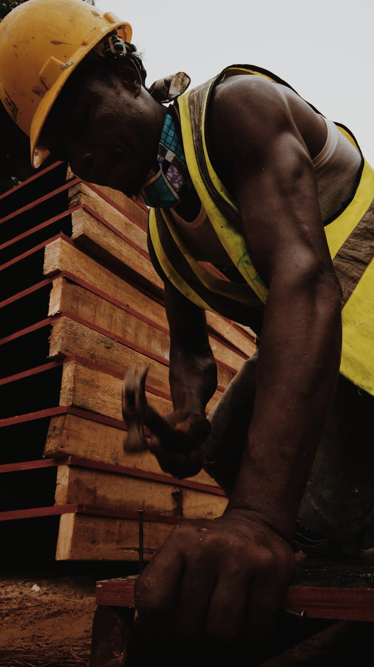 Focused Black Man Hammering Nail Working In Construction Site