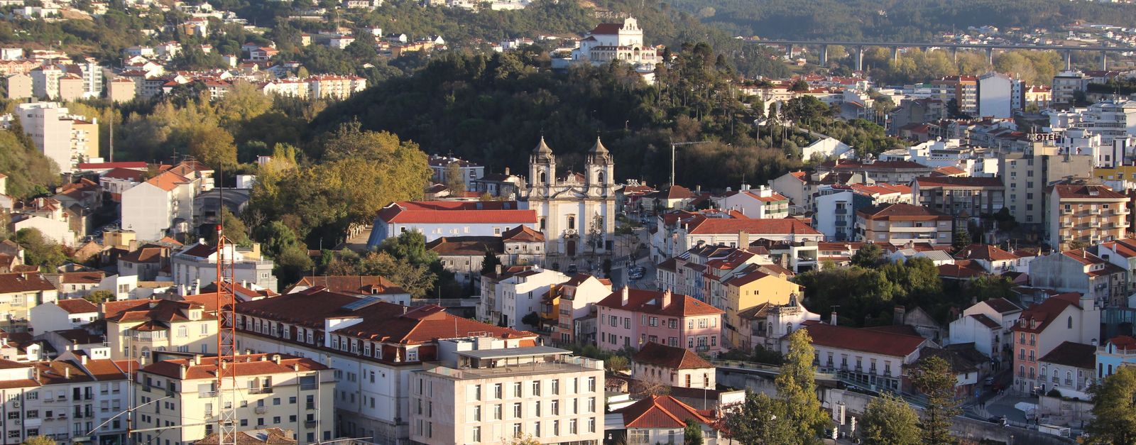 Aerial view of Leiria cityscape with historical buildings and lush hills in Portugal.