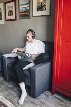 A man wearing headphones works comfortably on a laptop in a modern indoor setting.