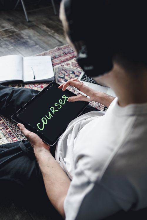 Free Individual wearing headphones using a digital tablet for online learning. Indoors setting. Stock Photo