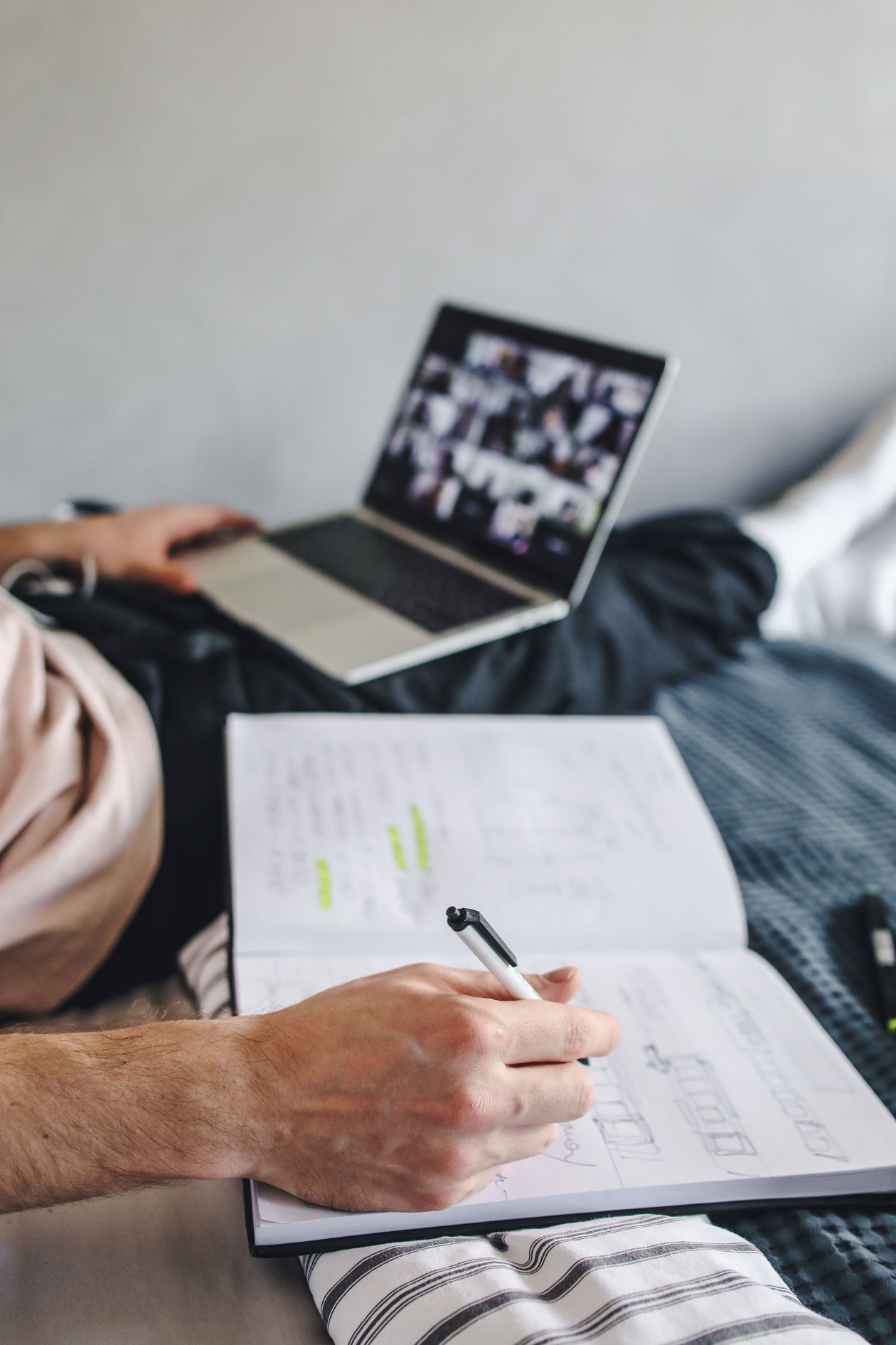 A student writing study notes while following an online class