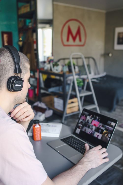 Free A man attentively participates in a virtual meeting from home using a laptop. Stock Photo