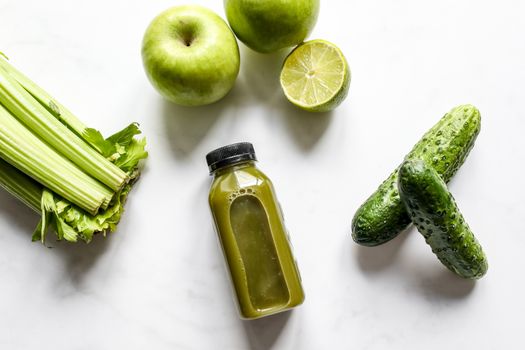 A top view of freshly extracted vegetable juice with celery, apples, lime, and cucumber.