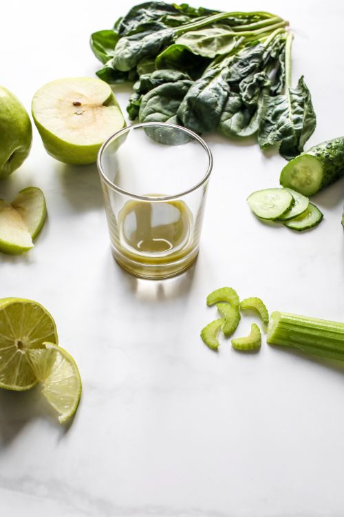 Free A vertical shot of fresh green ingredients around an empty glass on a white background, ideal for health-focused food content. Stock Photo