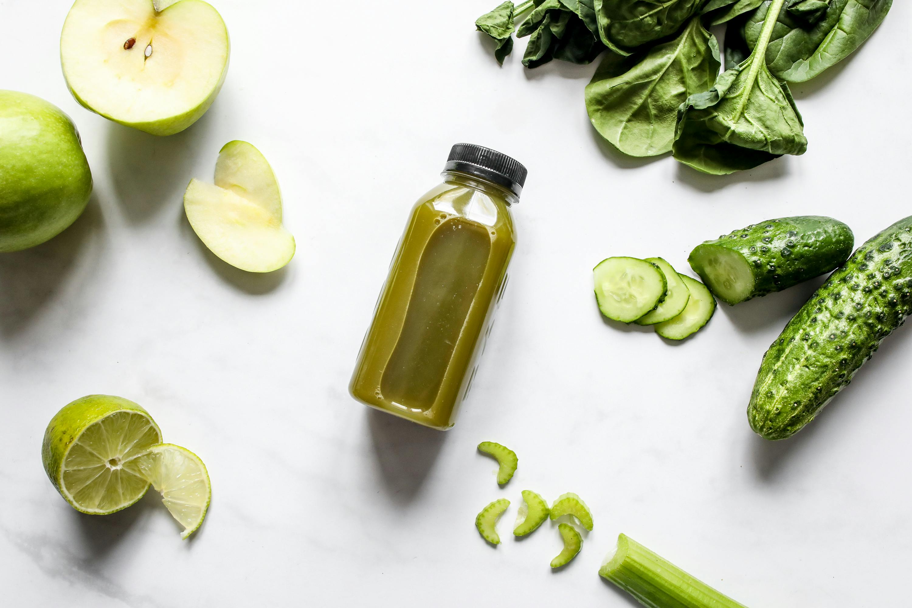 Free Discover fresh green juice surrounded by spinach, cucumber, apple, and lime. Stock Photo