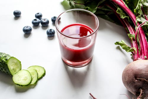 Red Juice in a Glass Beside Cucumber and Beetroot