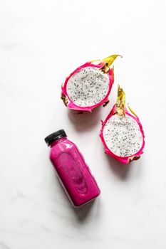 白色背景上，火龙果切片和一瓶充满活力的粉色冰沙的顶视图