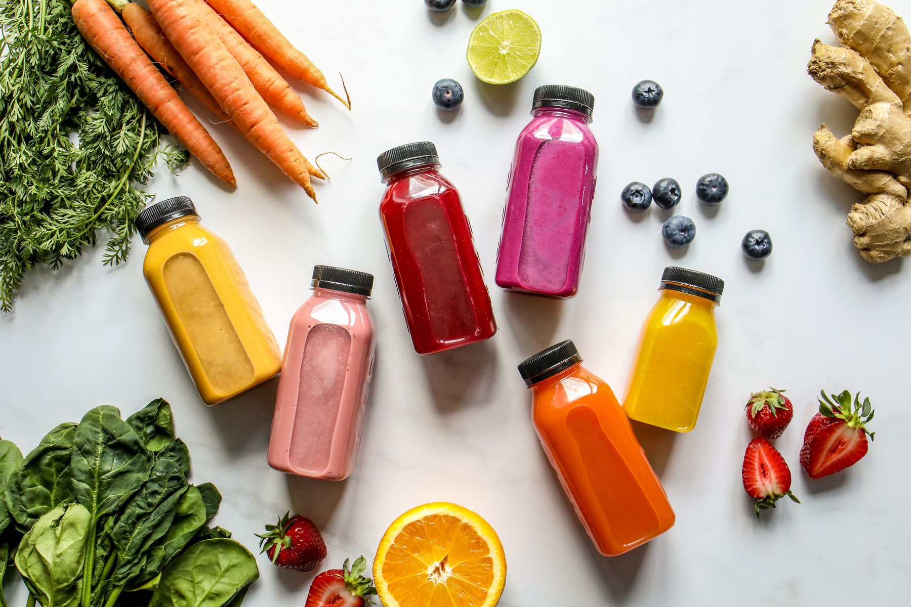 Colourful fresh juices surrounded by fruit and vegetables