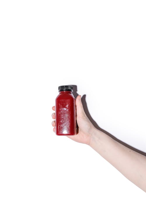 Person Holding Bottle with Red Juice