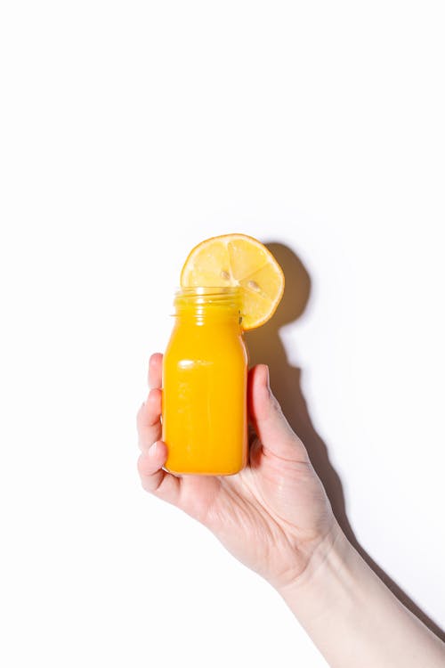 Person Holding Bottle with Orange Juice