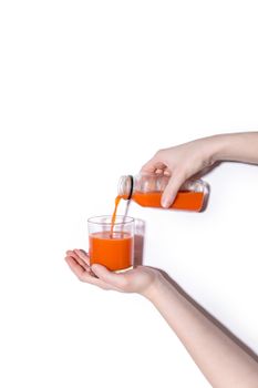 用手握住的瓶子将充满活力的胡萝卜汁倒入玻璃杯中