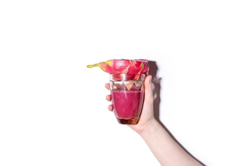 Free Person Holding Glass with Pink Smoothie and Dragon Fruit Stock Photo
