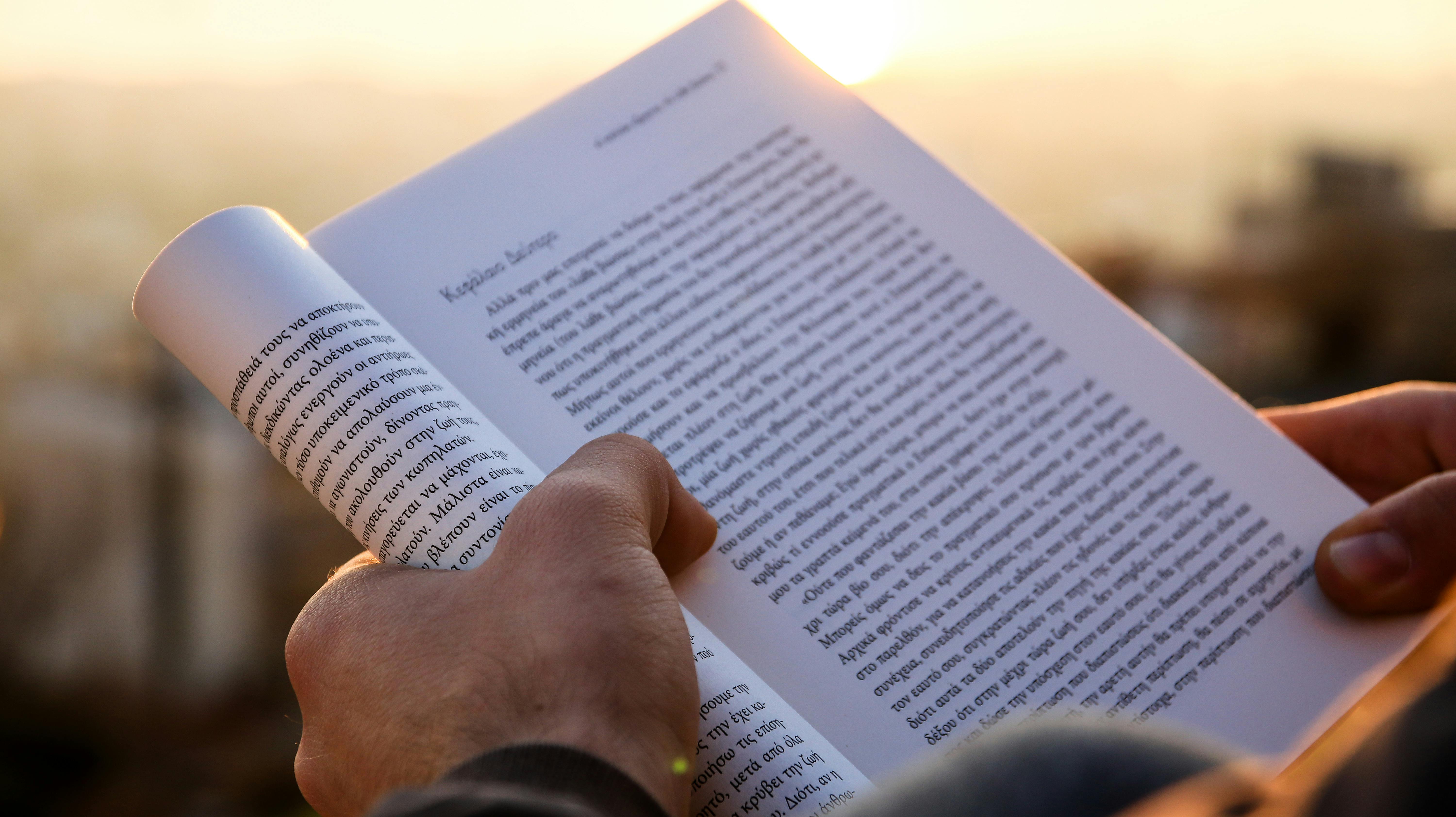 person holding a book during sunset