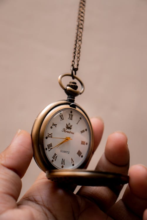 Person Holding Gold Pocket Watch