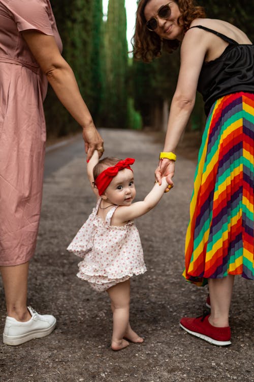 Menina Com Vestido Floral Branco Azul E Vermelho Segurando Um Brinquedo De Plástico Vermelho E Amarelo