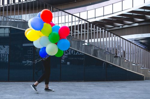 Free A person carries vibrant balloons up a modern stairway in Zapopan, Mexico. Stock Photo