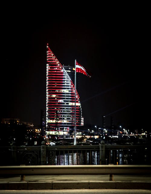 Illuminated modern glass tower on riverside at night