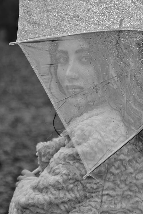 Positive woman under transparent umbrella on street