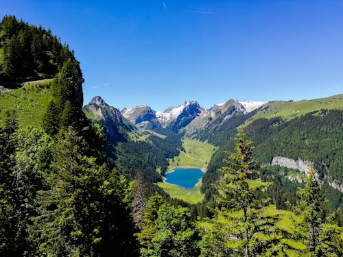 Body of Water Beside Mountain Under Blue Sky