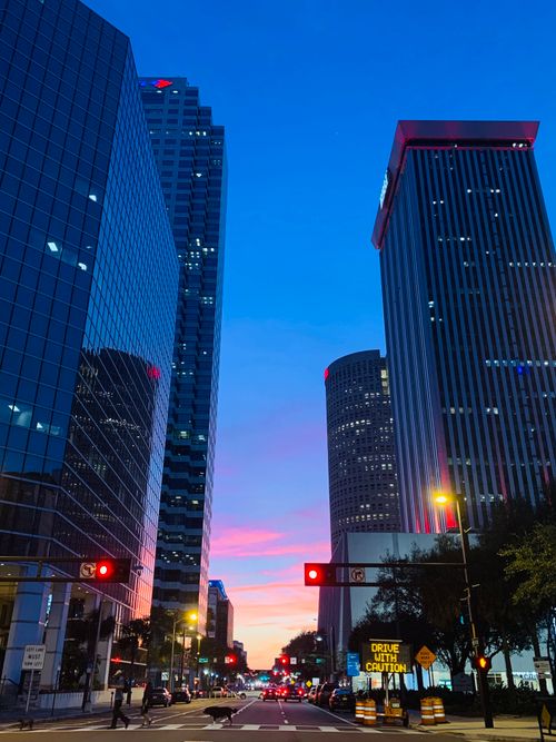 Free Modern futuristic skyscrapers located beside urban asphalt road and reflecting evening sky in glass walls in contemporary metropolis Stock Photo
