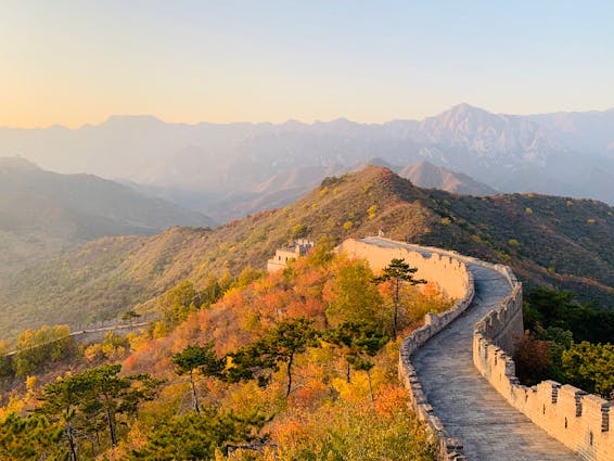 Picturesque landscape of Great Wall of China on hill with green trees and mountains on background on sunny day