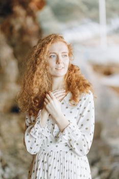 一位卷发、身着圆点连衣裙的宁静女子，在柔和的灯光下于户外摆着姿势