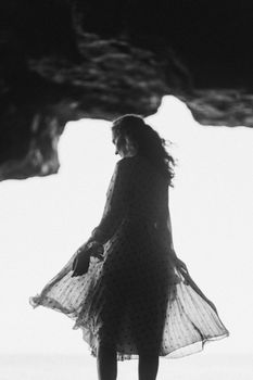 山洞里，一个女人穿着圆点连衣裙，以黑白剪影的姿态站立着