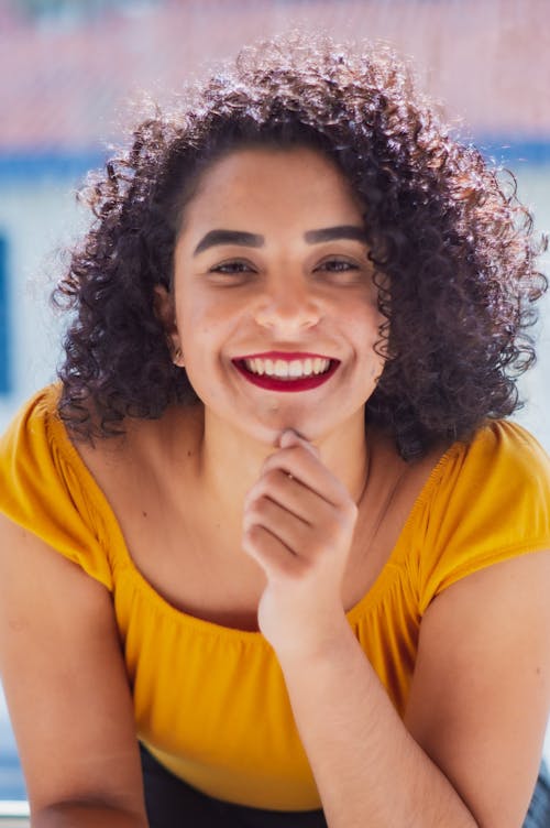 Free Joyful Hispanic woman touching chin on sunny day Stock Photo