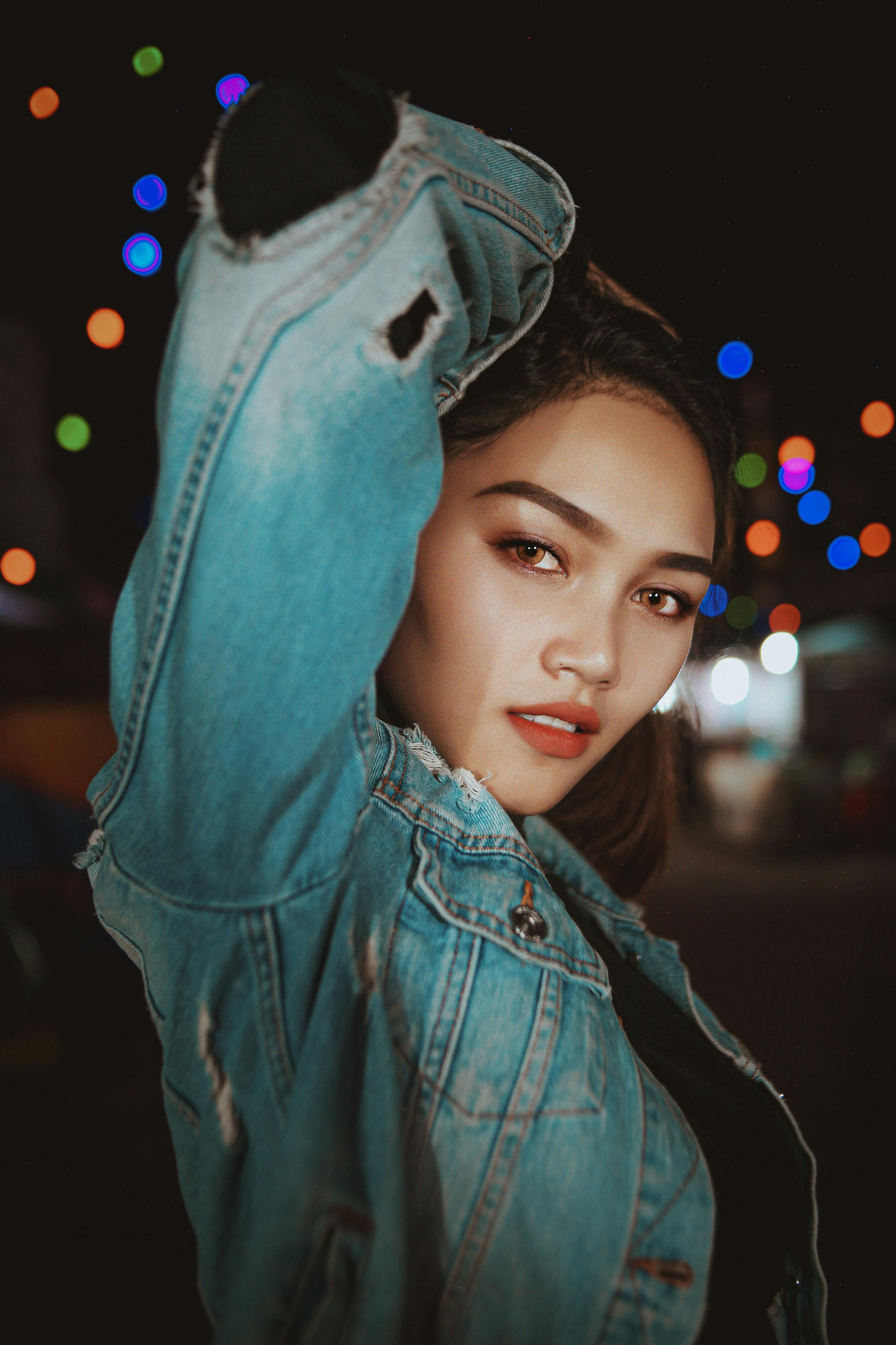 Young woman in denim jacket on illuminated street · Free Stock Photo