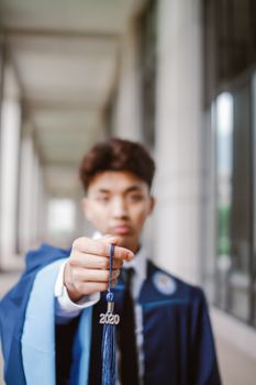 年轻毕业生手持2020年的流苏，象征着成就与未来的机遇