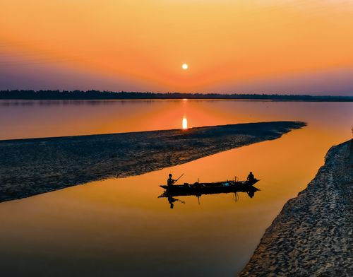 Free High angle of silhouette of people in boat fishing near sandy shore in evening Stock Photo