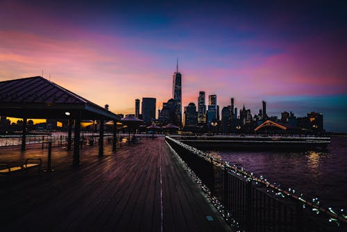 Brown Wooden Dock Near City Buildings during Sunset