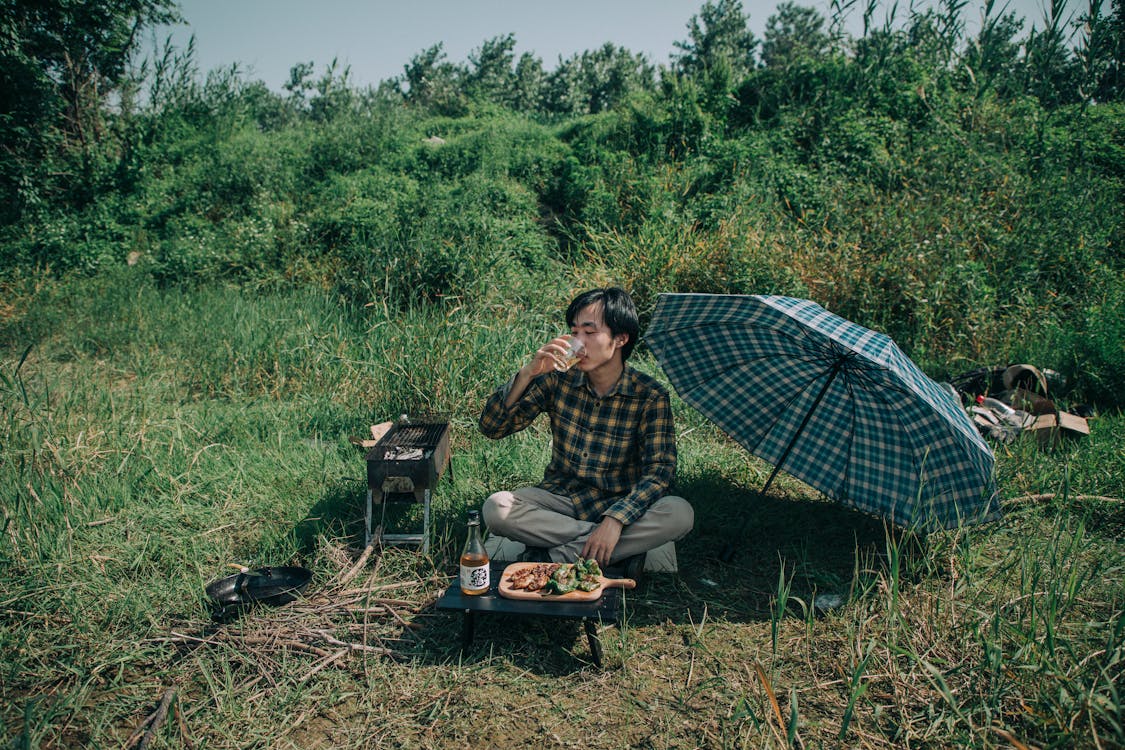 Free Photo of Man Drinking While Sitting on Grass Field Stock Photo