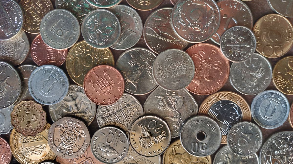 Diverse collection of world coins in a flat lay arrangement, showcasing different currencies and designs.