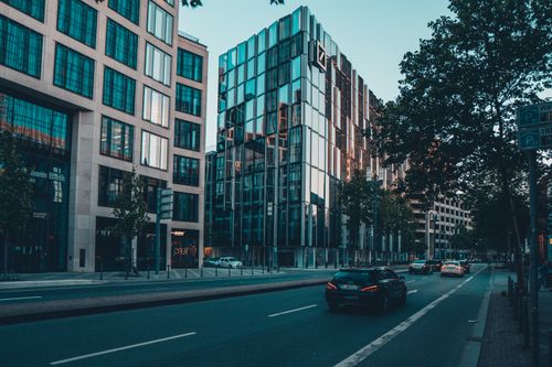 Free A bustling urban street features modern glass buildings and moving cars during the day. Stock Photo