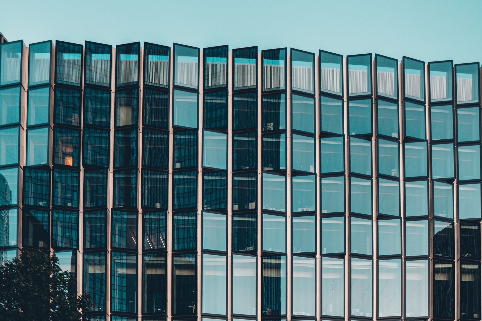 Contemporary office building with glass facade reflecting urban skyline on a sunny day.