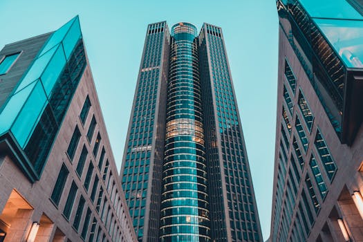 Low angle view of modern skyscrapers with geometric designs against a clear sky.