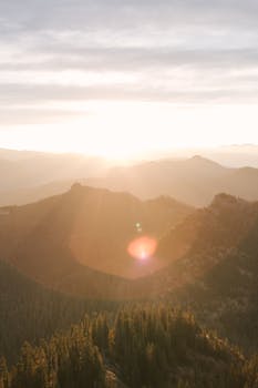 Breathtaking sunrise over Mount Rainier showcasing misty mountains and vibrant sunrays.