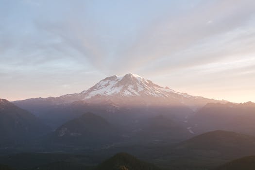 A breathtaking sunrise over Mount Rainier with snow-capped peaks and atmospheric mist.