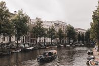 在多云的天空下，阿姆斯特丹运河边排列着历史建筑和船只