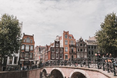 Free Charming view of Amsterdam's canal with iconic Dutch buildings and bicycles on a bridge, capturing the essence of the city. Stock Photo