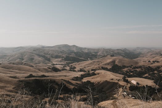 Expansive view of California's rolling hills and open sky, captured at dusk, showcasing natural beauty.