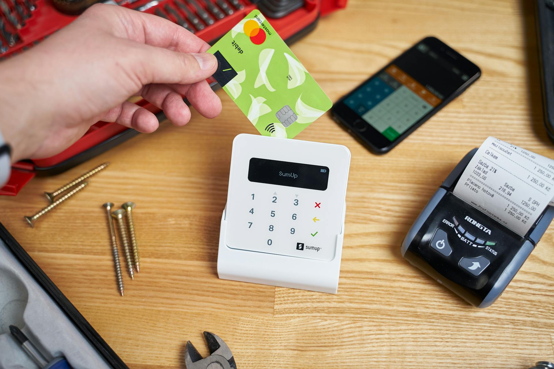 Close-up of a contactless transaction using a SumUp device and a bank card with tools nearby.