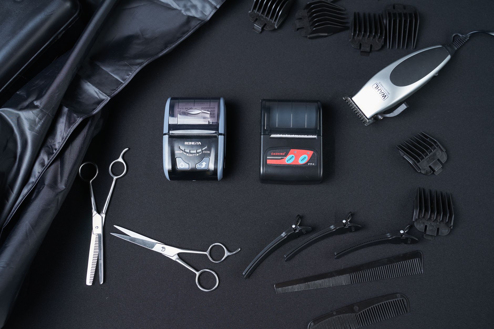 Overhead view of modern cash registers surrounded by hairdressing scissors and hairpins composing with clippers and combs